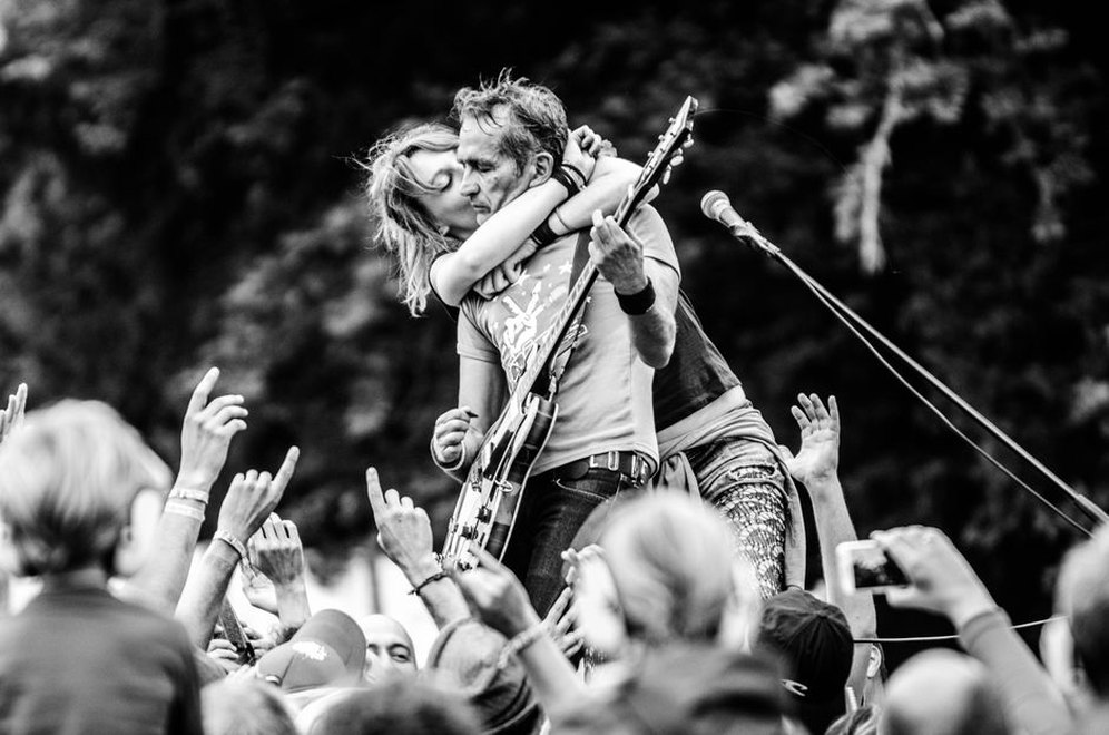 A guitarist performing before a festival crowd