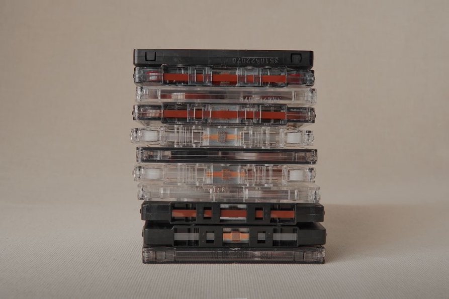 A pile of worn underground metal magazines next to dubbed cassette tapes and a pen