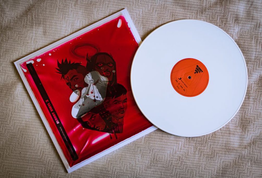 a turntable playing a vinyl record with a split EP sleeve showing two distinct band logos and monochrome illustrations